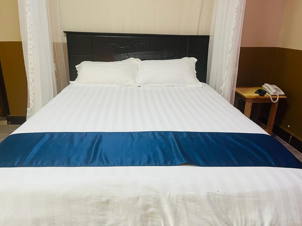 a large bed with a blue and white comforter at Gator's Hotel Kasese in Kasese