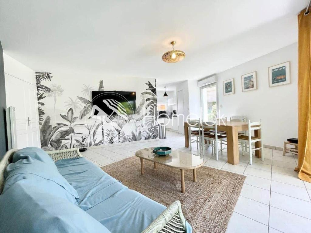 een woonkamer met een blauwe bank en een tafel bij Charmant T3 Ultra cosy - Jardin - 50m des plages in Ploemeur
