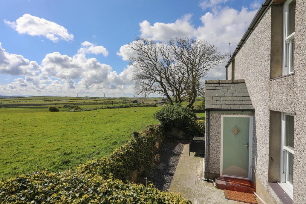 a house with a green door and a field at Tregynrig Bach in Cemaes Bay