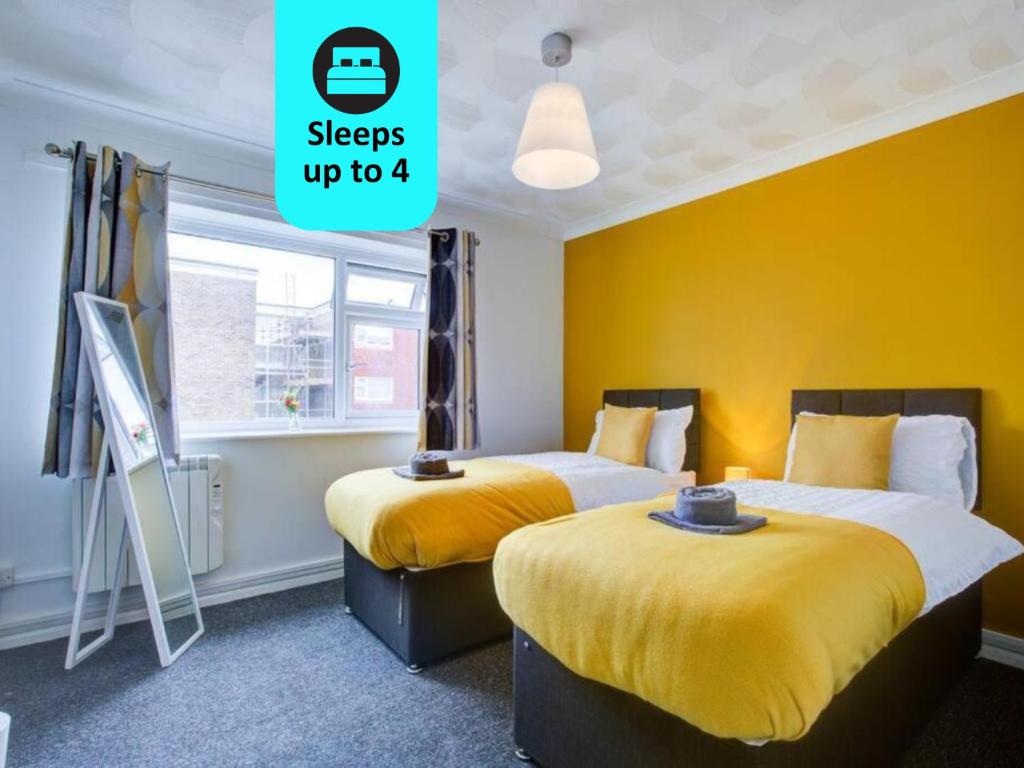 2 camas en una habitación con paredes amarillas en Lovely 2 Bed Apartment near the Sea en Lancing