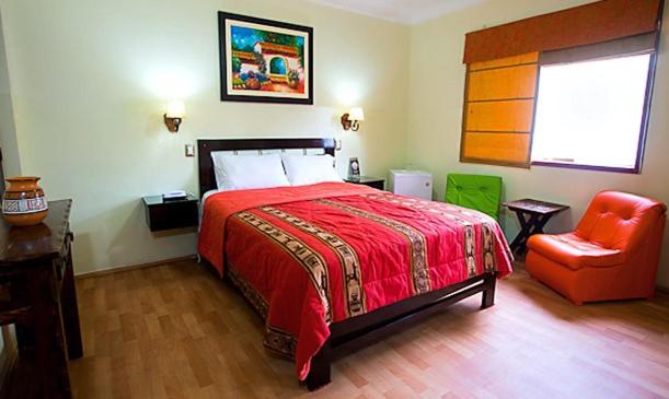 a bedroom with a red bed and a chair at Hotel Tinkus Inn in Lima