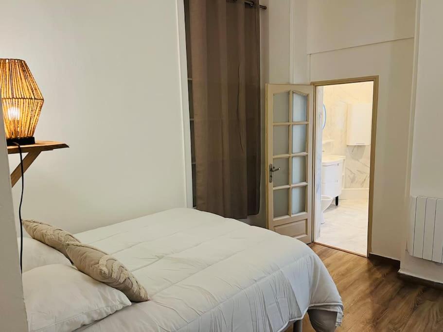 een slaapkamer met een wit bed en een deur naar een badkamer bij Le Petit Paradis : 2-4 pers WIFI in Boulogne-sur-Mer