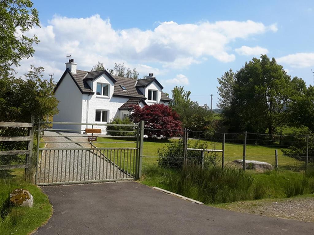una casa blanca con una valla delante en Rowanhill Cottage en Acharacle