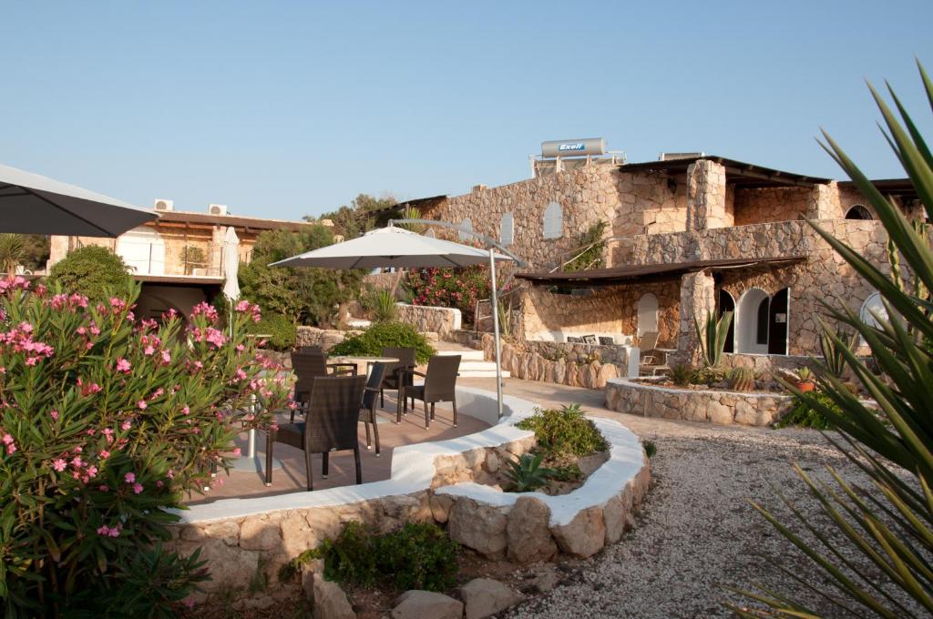 une terrasse avec des chaises et un parasol en face d'un bâtiment dans l'établissement Calamadonna Club Hotel, à Lampedusa