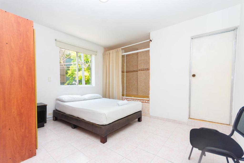 a bedroom with a bed and a window and a chair at Hotel Villa Real in Medellín