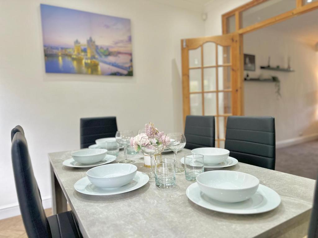 a table with plates and bowls and glasses on it at 3 Bed Entire House with WIFI, Parking and Garden Space in Enfield in Enfield Lock