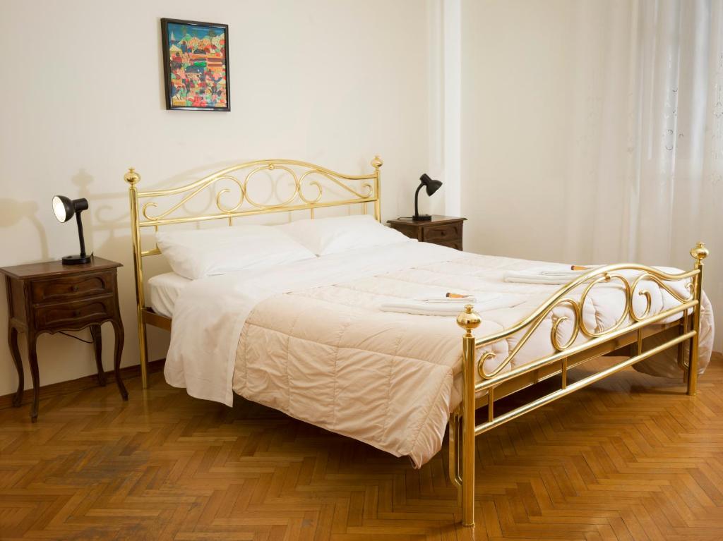 una camera da letto con un letto con lenzuola bianche e un pavimento in legno di Affittacamere di Andrea Bertolino Bologna a Bologna