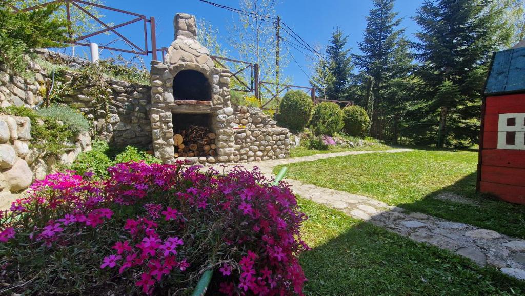 a garden with purple flowers and a stone oven at Chalet Mila in Mavrovo