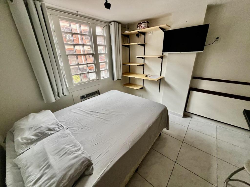 een kleine slaapkamer met een bed en een televisie bij Prático do residence in Natal