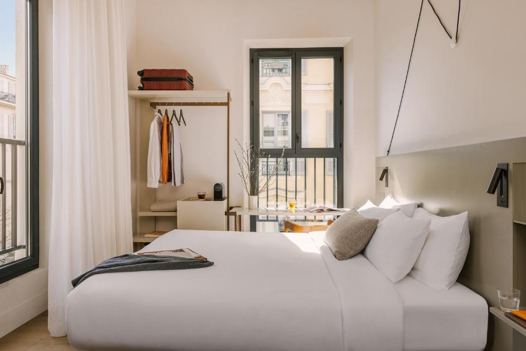 a white bedroom with a white bed and a window at Yelo Jean Médecin powered by Sonder in Nice