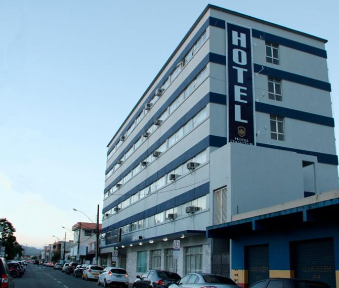 duży budynek przy ulicy miejskiej z zaparkowanymi samochodami w obiekcie Hotel Itajaí Tur - Itajaí Navegantes w mieście Itajaí