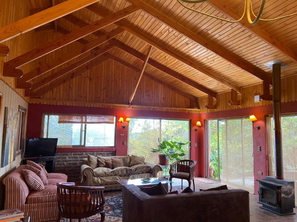 una sala de estar con sofás y techo de madera. en Cabaña Casa Tetelhue, en Colliguay