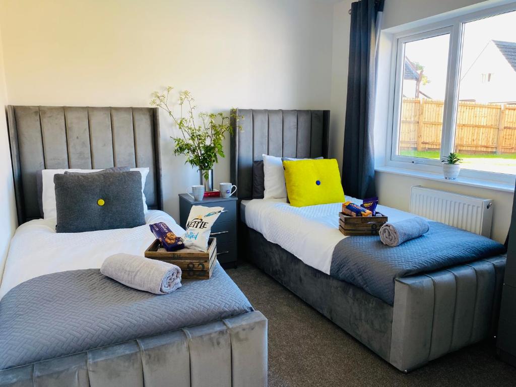 um quarto com 2 camas e uma janela em Blossom Lodge - 3 Bedroom Bungalow in Norfolk Perfect for Families and Groups of Friends em Narborough