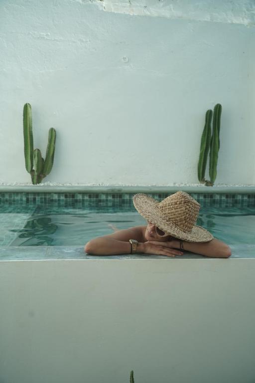 a woman in a hat laying in a swimming pool at Casablanca Hotel - Centro Histórico in Santa Marta