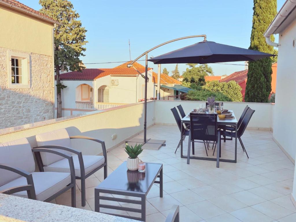 a patio with a table and chairs and an umbrella at Apartment Jukich in Sveti Filip i Jakov
