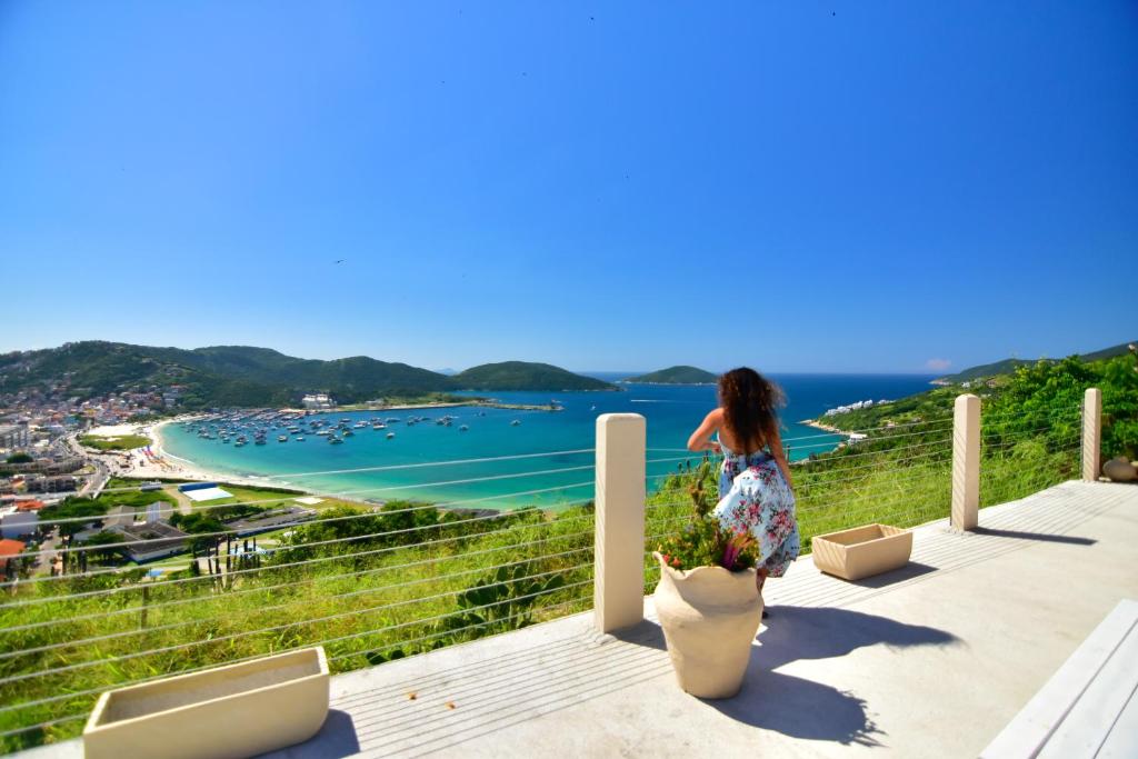 a woman standing on a balcony looking at the ocean at Pousada Tanto Mar in Arraial do Cabo