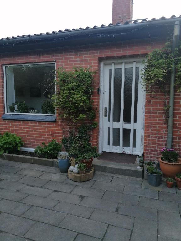 a brick house with a white door and potted plants at B&B Tvolm Ydby Thy in Tvolm