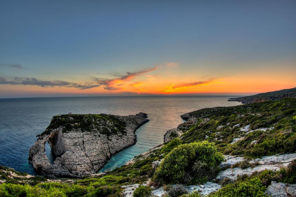a large rock in the ocean at sunset at Villa Roxa Montuoso in Agios Leon