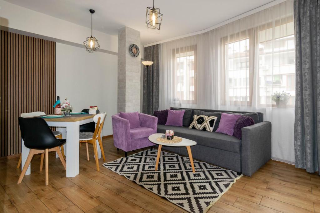 ein Wohnzimmer mit einem Sofa und einem Tisch in der Unterkunft Joy Apartment Burgas center private parking in Burgas City