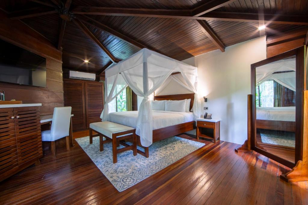 a bedroom with a bed and a desk and a mirror at Chachagua Rainforest Hotel & Hot Springs in Fortuna