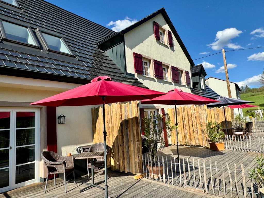 deux parapluies rouges sur une terrasse devant une maison dans l'établissement Boardingroom Seifersreuth, à Grafengehaig