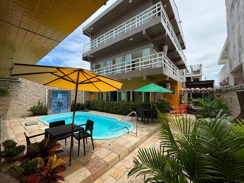 uma piscina com uma mesa e cadeiras e um guarda-sol em Pousada Residência dos Sonhos em Porto de Galinhas