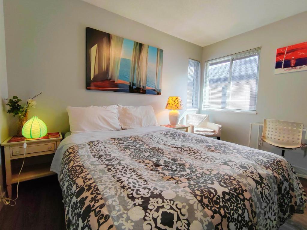 a bedroom with a bed and a table with a lamp at Bed Plus YVR in Richmond