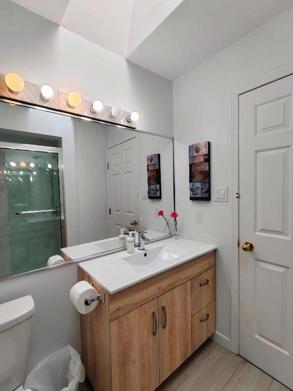 a bathroom with a sink and a toilet and a mirror at Bed Plus YVR in Richmond