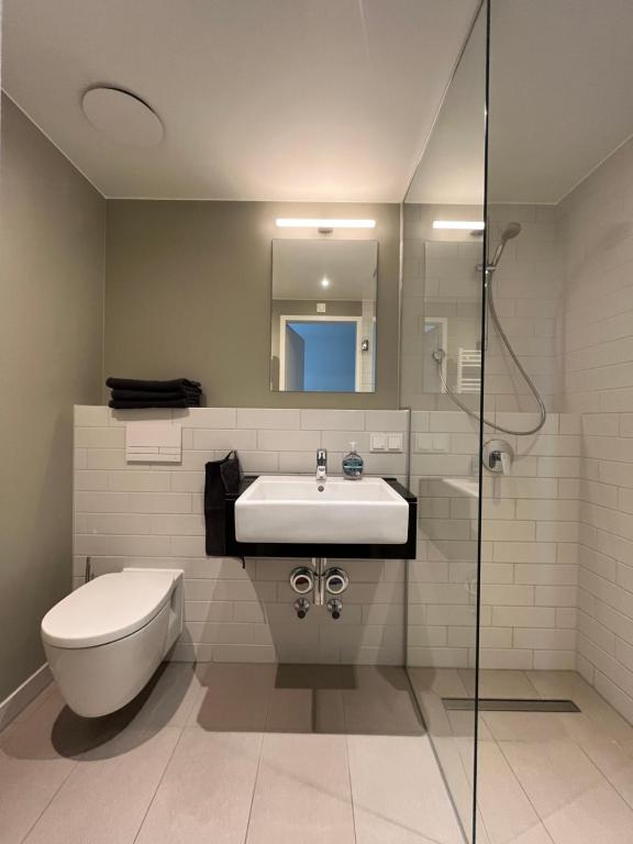a bathroom with a sink and a toilet and a shower at Studio Apartment über den Wolken in Berlin