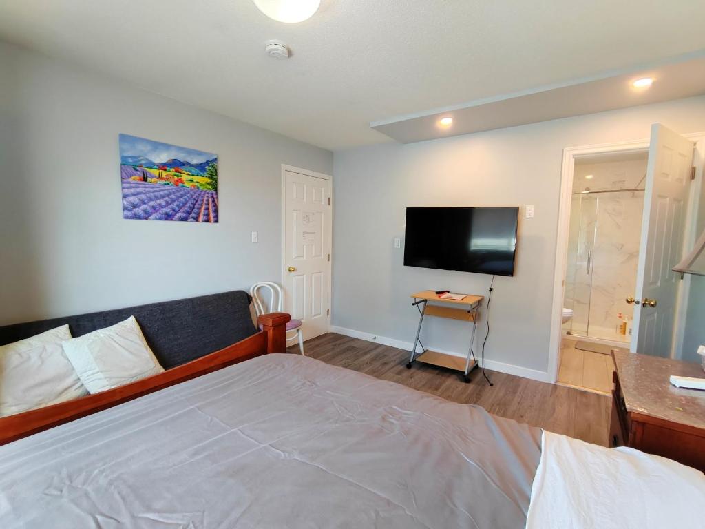 a bedroom with a bed and a flat screen tv at Bed Plus YVR in Richmond