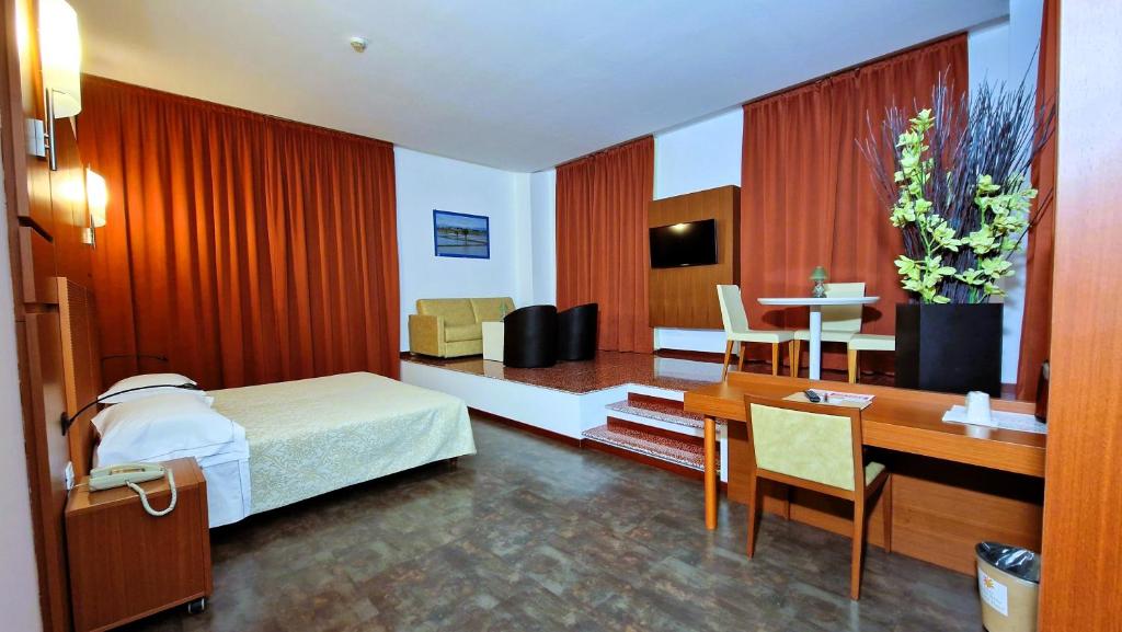 una camera d'albergo con letto, scrivania e tavolo di Bella Italia Palace Hotel a Novara