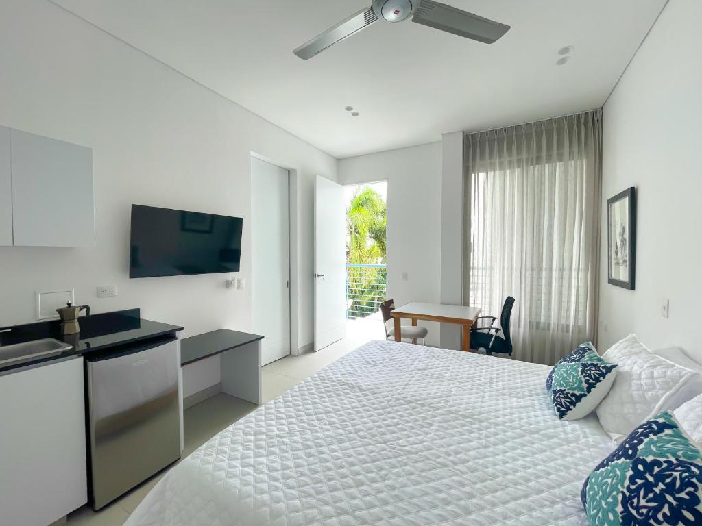 a white bedroom with a bed and a television at Apartaestudio Brumilo 2 in Montería