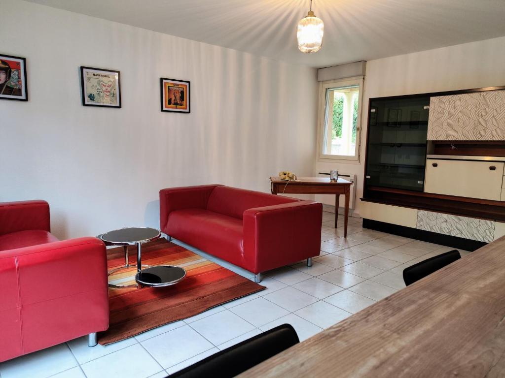 een woonkamer met rode meubels en een grote televisie bij La curieuse petite maison in Vendôme