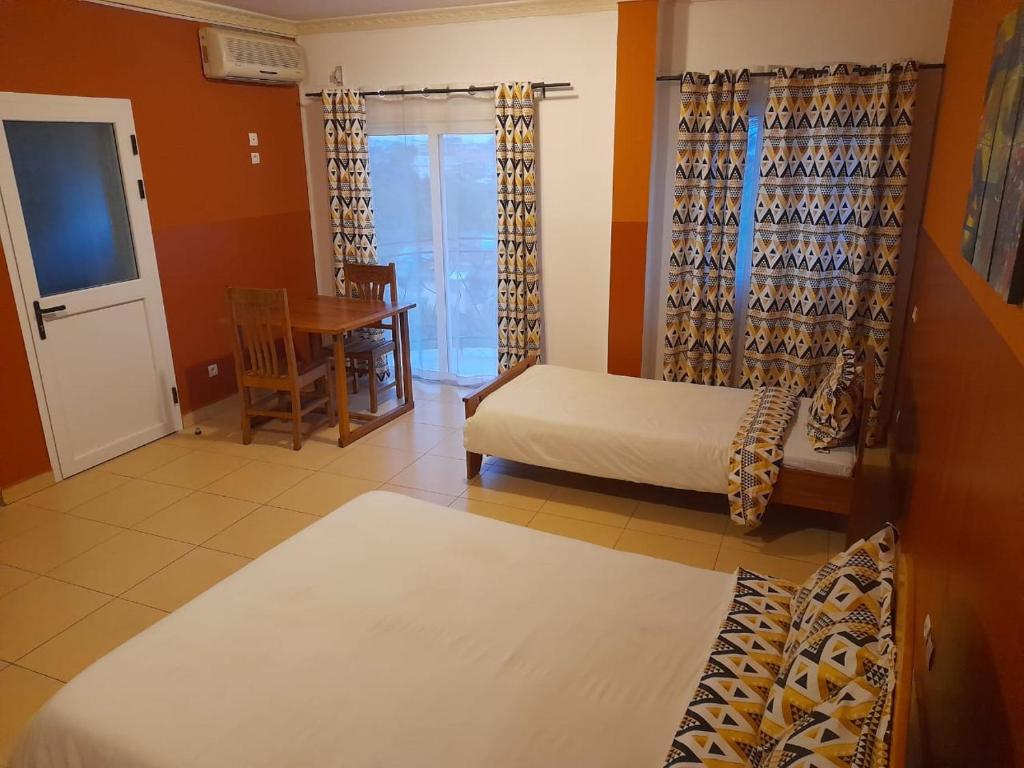 a room with two beds and a table and a table at Hôtel les Cygnes II in Antananarivo