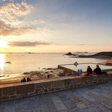 Un groupe de personnes assises sur un mur face à l'océan dans l'établissement Studio à 100m à pied de la plage et de la digue du sillon, à Saint-Malo