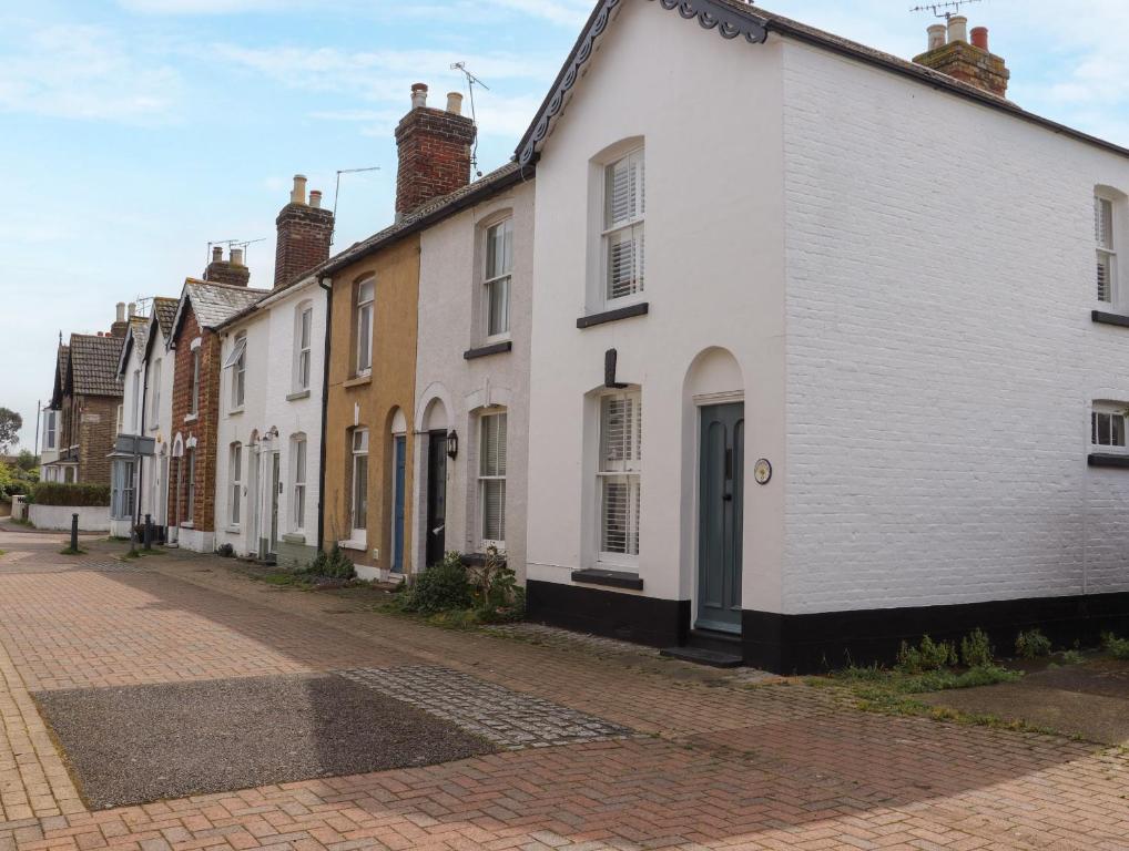 una fila de casas blancas en una calle adoquinada en Fishermans Cottage en Whitstable