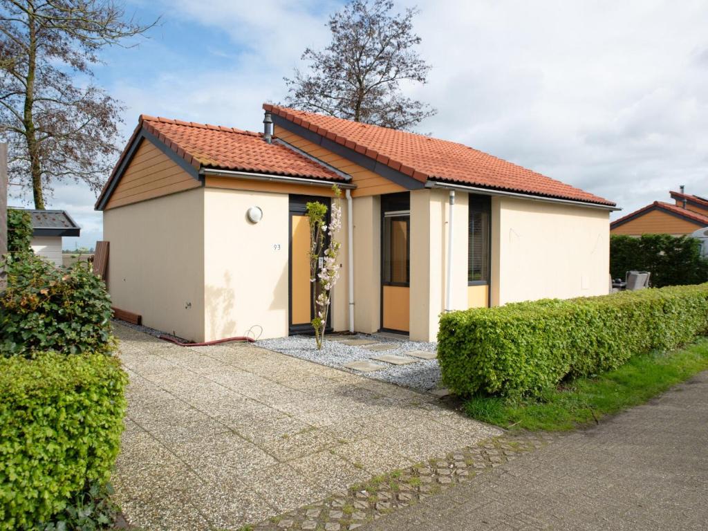 uma pequena casa branca com um telhado vermelho em Wellness Bungalow with whirlpool and sauna em Zevenhuizen