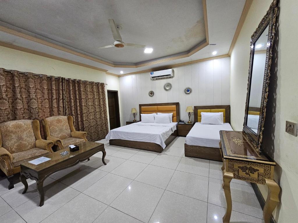 a hotel room with two beds and a couch and a table at Sweet Express Gulberg in Lahore