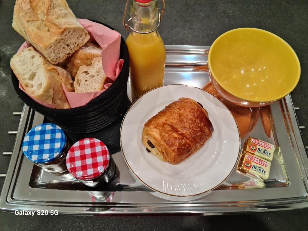 a tray with a plate of food with bread and orange juice at L'Adeline Escapade de Charme et Calme proche Guédelon in Bléneau