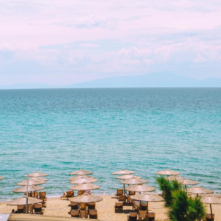 a group of umbrellas and chairs on the beach at Bohemian Dreamscape #PROPERTLY in Hanioti