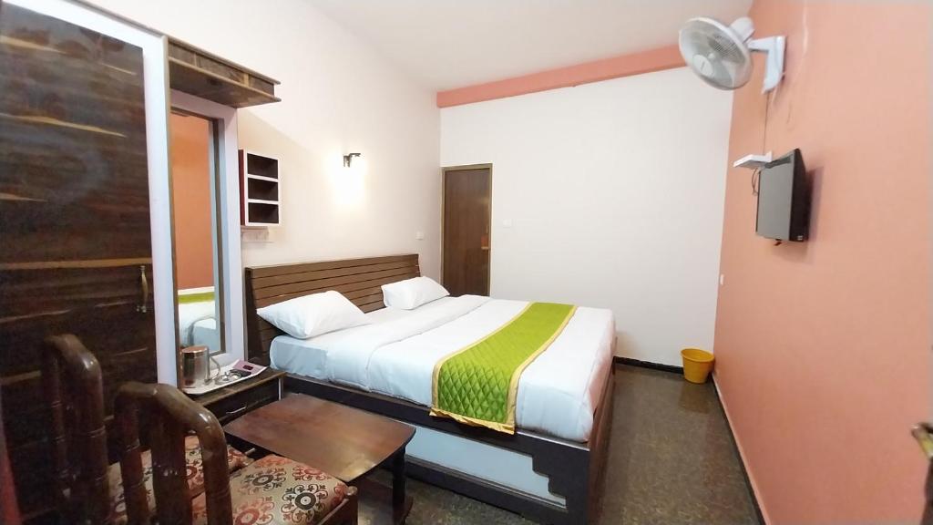 a small bedroom with a bed and a chair at SV RESIDENCY in Ooty