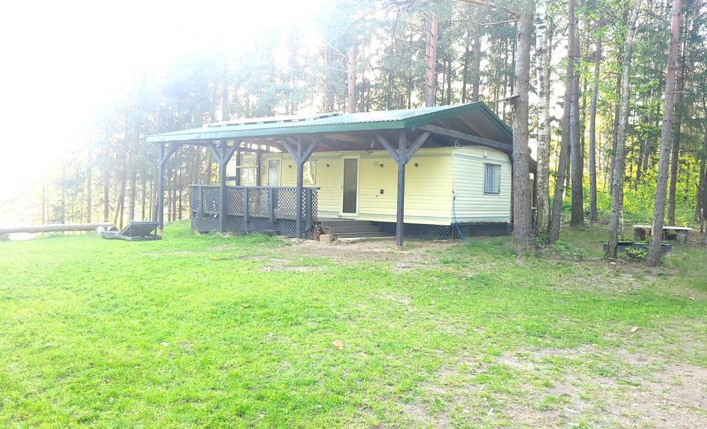 a small yellow house with a green roof in a field at EKO Domek u Siemion in Raczki