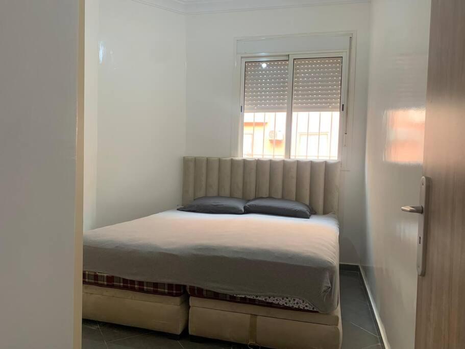 Bett in einem Zimmer mit Fenster in der Unterkunft Spacieux appartement 2 chambres 1 salon à 5 minute de l aéroport Marrakech Ménara in Marrakesch