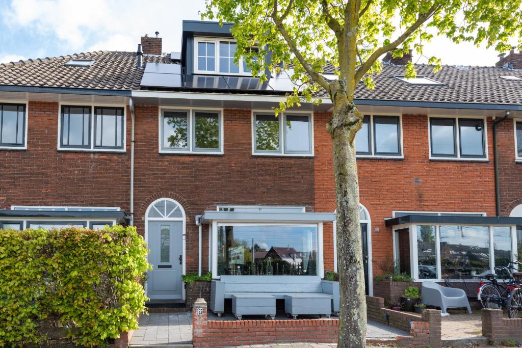 ein Backsteinhaus mit weißen Fenstern und einem Baum in der Unterkunft Beautiful house n.Amsterdam, suitable for families in Hilversum