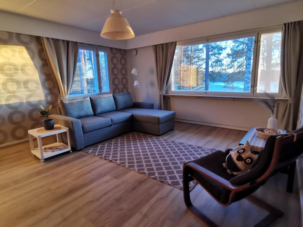 a living room with a blue couch and two windows at Vuori Camp by Saimaa in Vuoriniemi