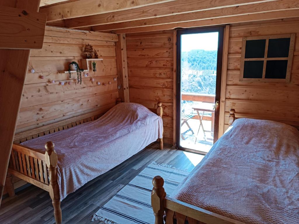 1 dormitorio con 2 camas en una cabaña de madera en Avlija Biberović, en Sjenica