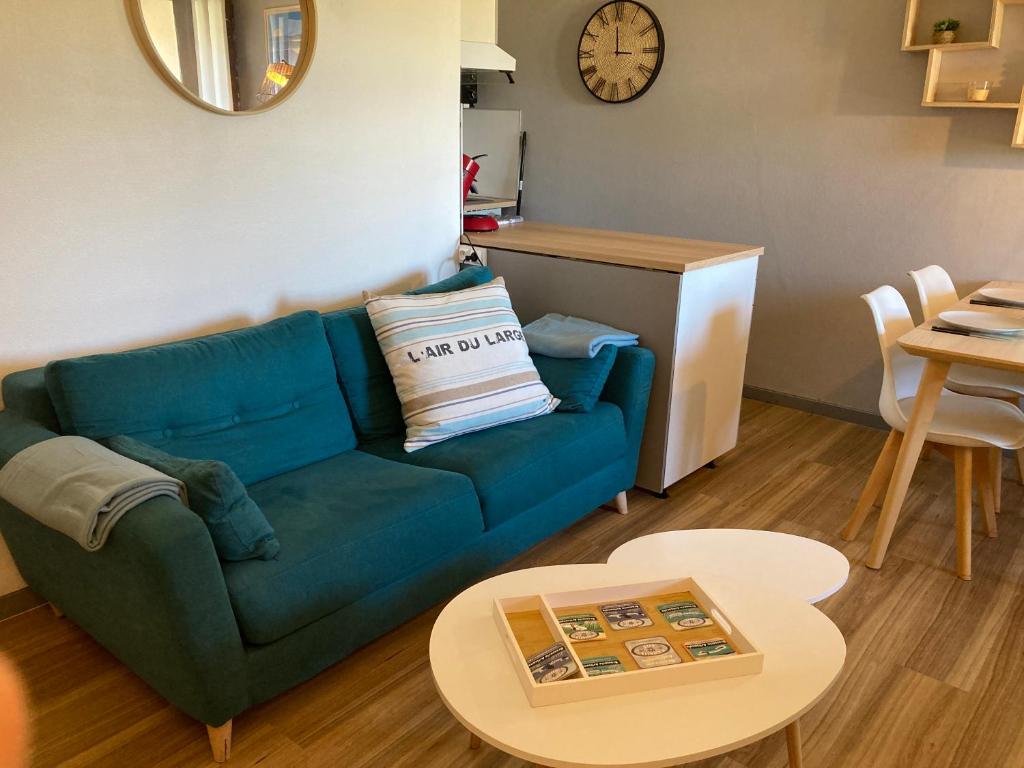 sala de estar con sofá azul y mesa en Appartement cosy à quelques pas de l'océan, en Biscarrosse