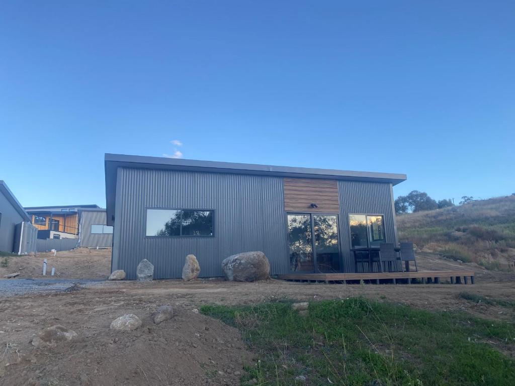 a small metal building with a porch and some rocks at Hygge Eco Cabins in Jindabyne