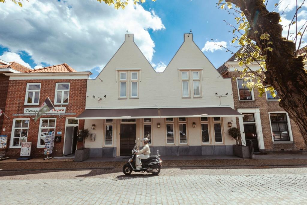 una mujer montando un scooter delante de un edificio en Hotel de MAGISTRAAT en Willemstad