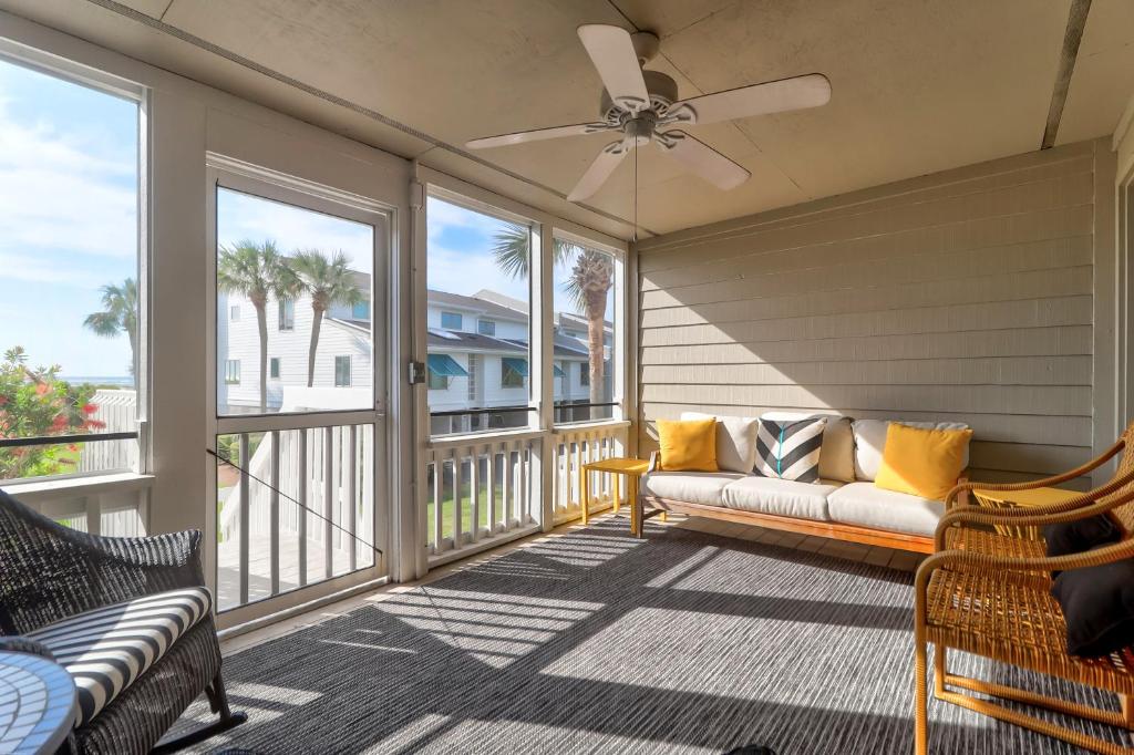 a screened in porch with a couch and a ceiling fan at 62 Beach Club Villa in Isle of Palms